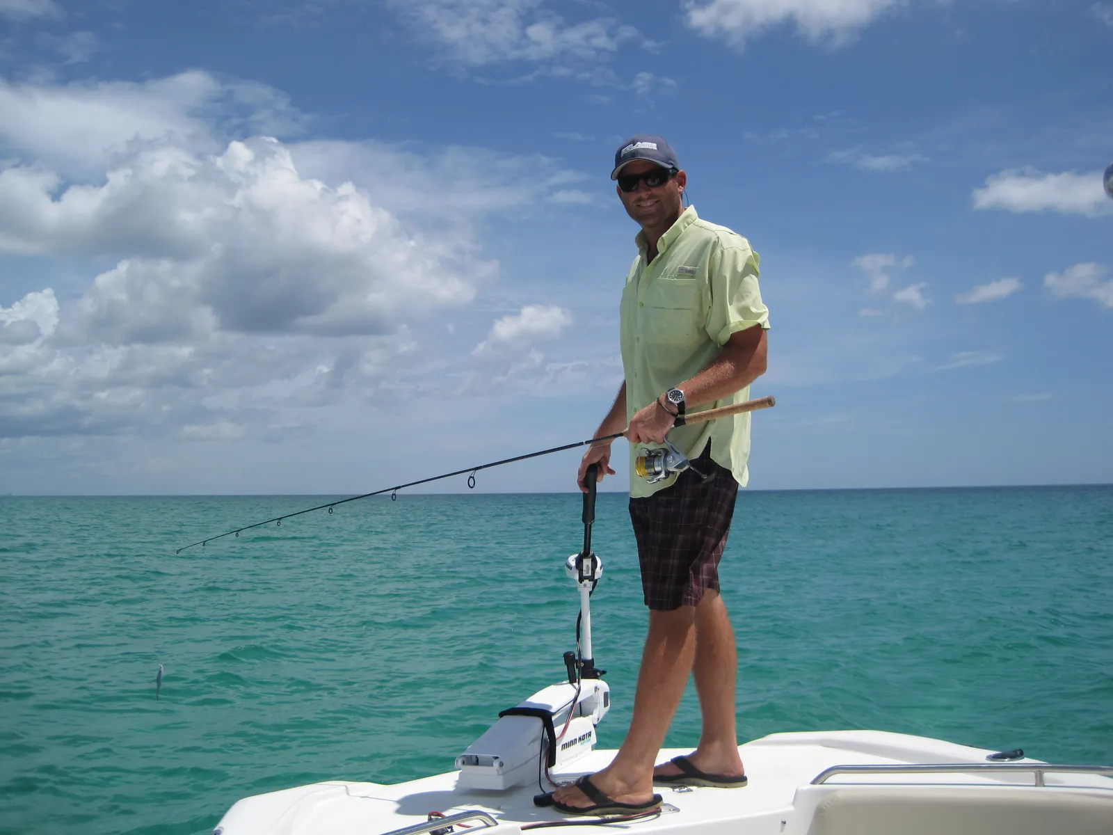Captain Mike Bauman fishing from the bow of his boat on clear turquoise Gulf water