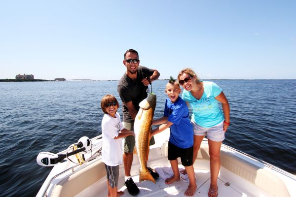 A smiling family holding a big bull redfish on Captain Mike's boat