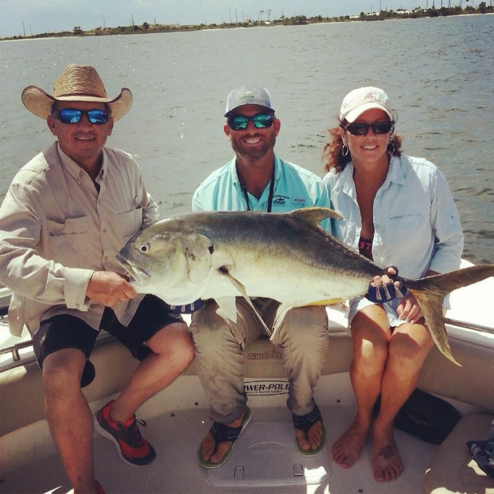 Captain Mike with two guests holding a big jack crevalle on the boat