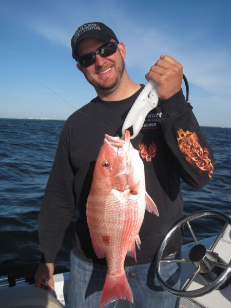 A smiling angler holding a red snapper